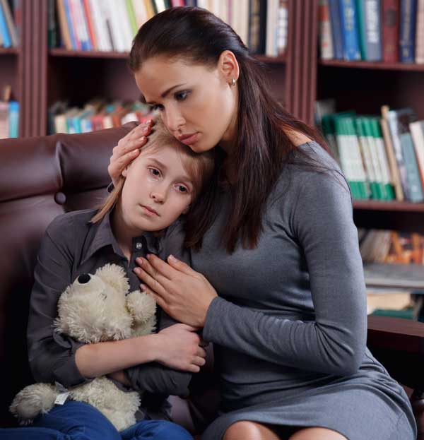 Sad child being comforted by a woman