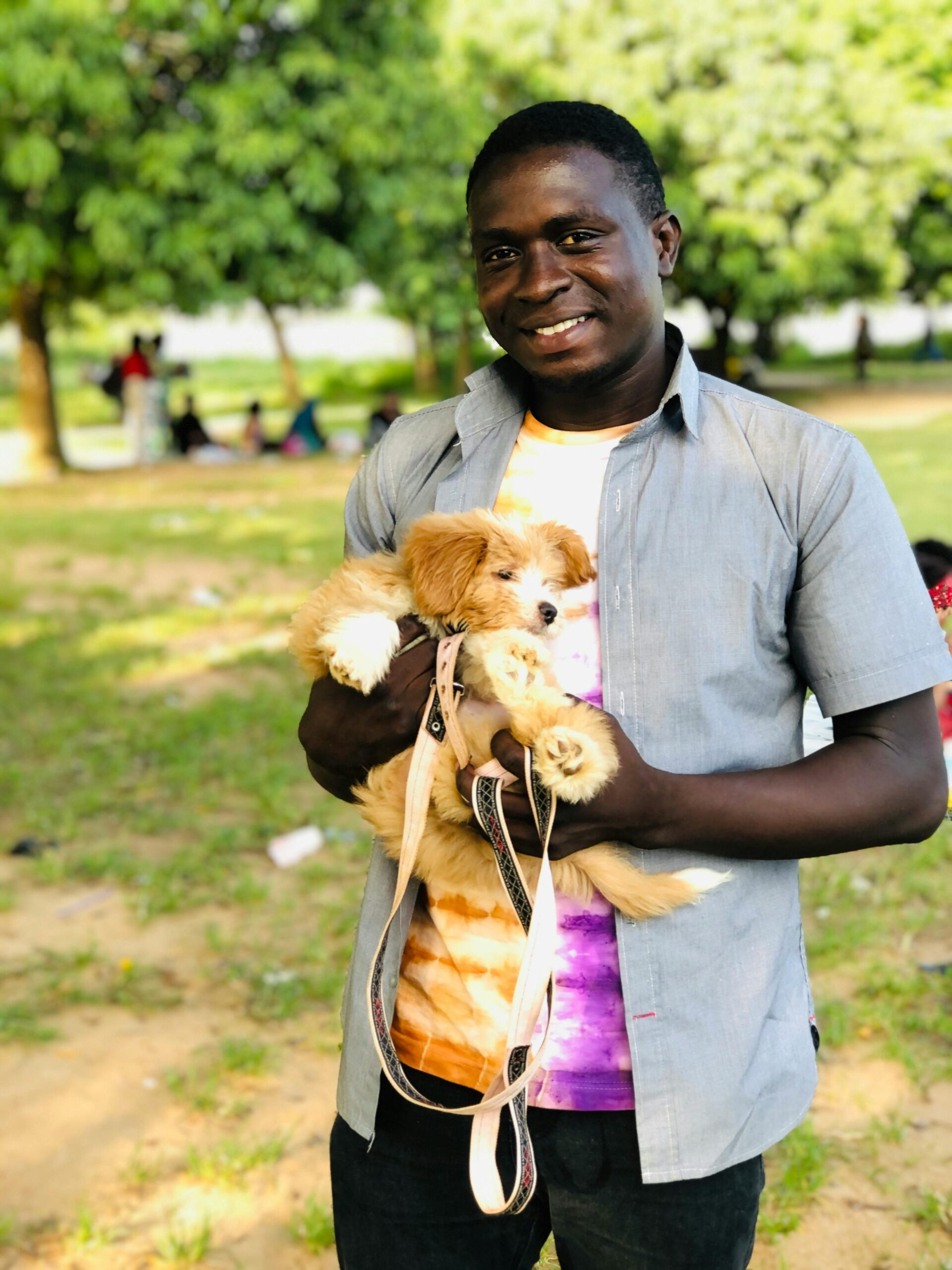 young black man holding dog in a park